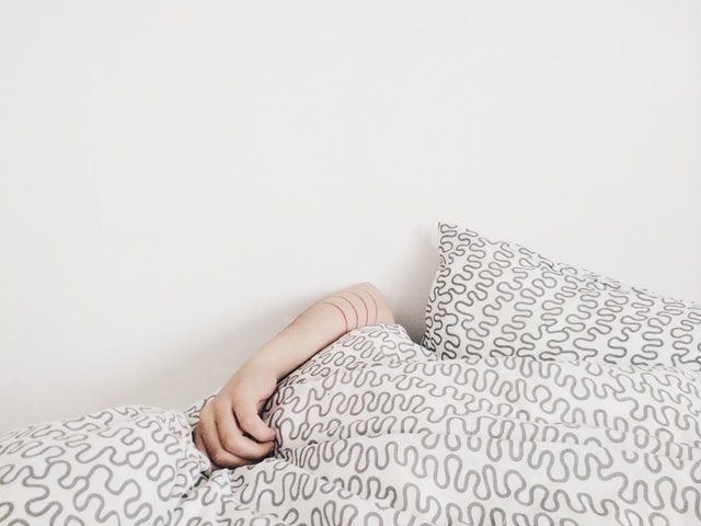 A person under the covers. Photo by elizabeth lies