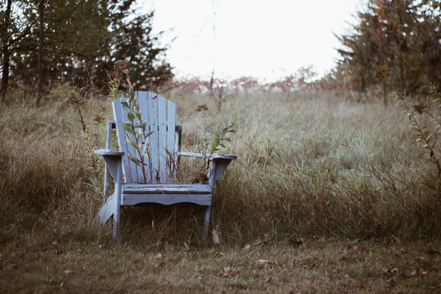 old deck chair sitting in a field of tall grass